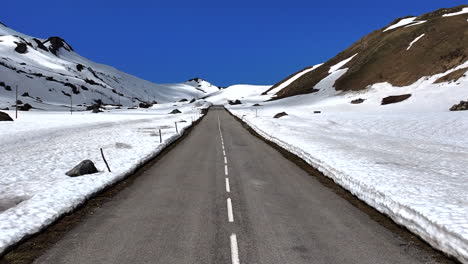 Front-Aerial-Centered-Dolly-Empty-Alpine-Road-Snow-Spring-Blue-Sky-Pass-Cormet-Roselend-Savoie-France
