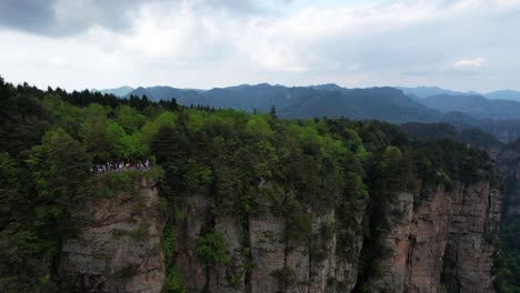 Aerial-dolly-out-shot-viewpoint-with-tourists-revealing-mountainous-landscape-in-Zhangjiajie-National-Forest-Park,-China