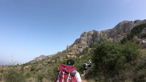 Hikers-group-with-gear-backpack-heading-towards-the-mountain,-Alicante-Spain