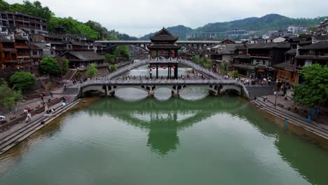 Aerial-pullback-from-Snow-Bridge-over-Tuo-Jiang-in-Phoenix-Ancient-Town,-China