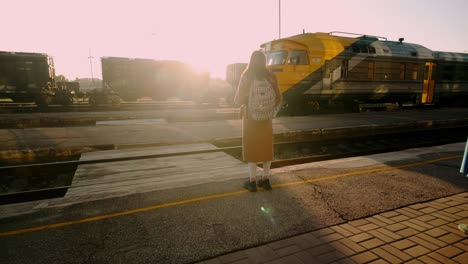 Sunlight-flashes-through-a-passing-train,-illuminating-a-young-lady-traveling-with-a-backpack,-capturing-the-essence-of-journey-and-adventure