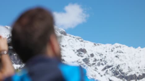 Rack-focus-between-back-of-man's-head-and-snowy-mountain-peak