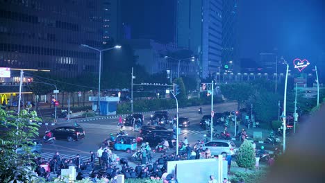 Thamrin-road-intersection-bustling-with-cars-motorbikes-illuminated-by-glow-from-billboard