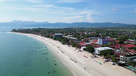 Vuelo-De-Drones-En-Una-Playa-En-Langkawi,-Malasia-Drone-Vuela-Hacia-Atrás-Sobre-La-Vista-Al-Mar-De-La-Naturaleza-Y-Los-Edificios-Del-Hotel-En-La-Playa