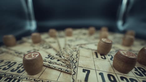 Crane-pull-backwards-shot-of-a-Bingo-desk-lottery-game,-vintage-cards-with-numbers,-wooden-chips,-super-slow-motion-120-fps,-studio-lights