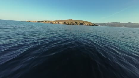 FPV-drone-flying-low-over-the-sea-towards-an-island-in-Greece