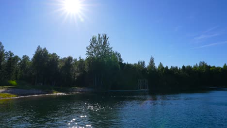 Bellas-Imágenes-De-Un-Lago-Rural-En-Estonia-Europa-En-4k-Durante-El-Verano-Donde-La-Cámara-Realiza-Una-Panorámica-Y-Muestra-La-Costa-Del-Lago,-Diferentes-Plantas-Y-árboles-Y-El-Cielo-Azul-En-La-Parte-Posterior-4k