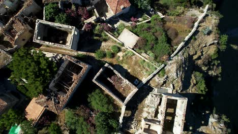 Aerial-View-of-Ruined-Stone-House-Walls,-Collapsed-Roofs-in-Coastal-Ionian-Village:-Medieval-Wall-History-at-Risk-in-Albania
