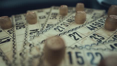 Crane-shot-of-a-Bingo-desk-lottery-game,-vintage-cards-with-numbers,-wooden-chips,-super-slow-motion-120-fps