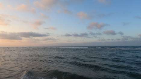 A-peaceful-pan-down-shot-from-the-sky,-showcasing-the-golden-hues-of-sunset-over-the-beach