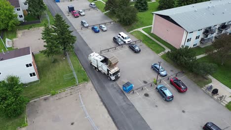 Camión-De-Basura-Recogiendo-Basura-En-Un-Estacionamiento,-Sin-Marca-De-Empresa