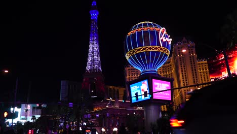 Paris-Casino-Hotel-Am-Las-Vegas-Strip-Bei-Nacht,-Eiffelturm-Und-Ballon-Nachbildungen-Im-Licht,-Menschen-Auf-Dem-Zebrastreifen