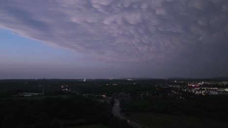 Storm-clouds-and-lighting-above-Springdale,-Arkansas-with-vehicle-traffic-with-drone-video-hyper-lapse-pulling-back