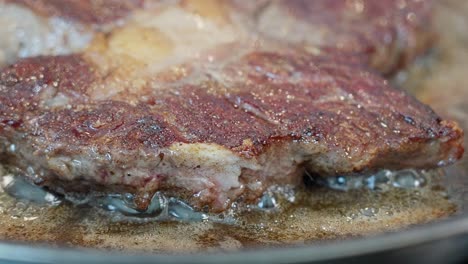 Detailed-closeup-of-entrecote-frying-in-butter,-showing-the-seared-crust-and-sizzling-edge-in-the-pan
