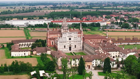 Drone-shot-of-Certosa-di-Pavia-cathedral-and-historical-monumental-complex-that-includes-a-monastery-a-sanctuary-and-courtyards-at-sunny-day