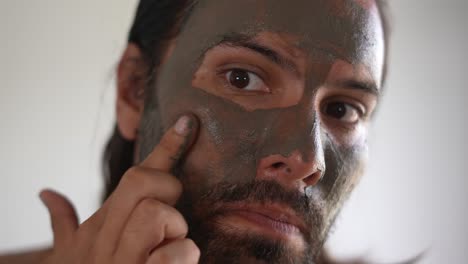 man-using-a-clay-mask-on-his-face,-relaxed