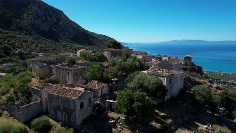 Pueblo-Pintoresco-En-Una-Colina-Rocosa-De-La-Costa-Jónica-Con-Casas-Tradicionales-De-Piedra-Con-Vistas-Al-Hermoso-Valle-De-Olivos-Mediterráneos-En-Albania