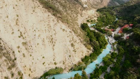 Fast-dolly-in-drone-flight-in-the-Mezquital-Canyon-looking-over-the-Tolantongo-River,-Grutas-de-Tolantongo,-Mexico