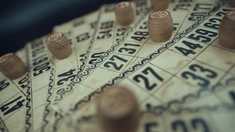 Crane-FPV-ROTATING-backwards-shot-of-a-Bingo-desk-lottery-game,-vintage-cards-with-numbers,-wooden-chips,-super-slow-motion-120-fps,-studio-lights