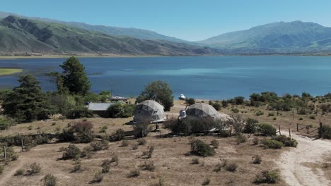 Beautiful-landscape-of-the-La-Angostura-dam-with-two-Glamping-domes-on-the-shore
