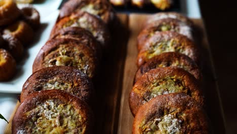 Round-baked-buns-with-savory-filing-on-wooden-board,-celebration-table