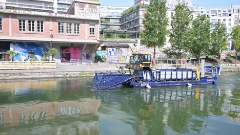 Special-boad-running-on-the-Saint-Martin-canal-collecting-dirt,-floating-object-above-the-water-in-effort-to-prepare-the-2024-Olympic-Games-in-Paris