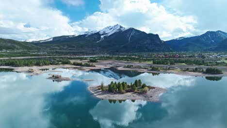 Aerial-dolly-over-calm-serene-water-reflecting-blue-sky-and-rocky-mountains-in-Frisco-Colorado