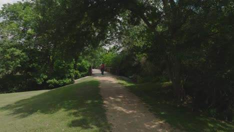 A-senior-male-cyclist-riding-a-fat-tire-e-bike-over-a-bridge-on-the-Armand-Bayou-Hike-and-Bike-Trail-in-Pasadena,-Texas