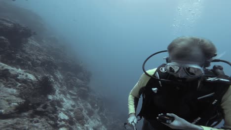 A-scuba-diver-checks-their-dive-computer-while-exploring-a-coral-reef-in-Raja-Ampat,-Indonesia