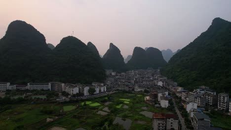 Drohnenrückzug-Steigt-Auf-Und-Enthüllt-Bei-Sonnenaufgang-Die-Stadt-Yangshuo-In-Den-Bergen