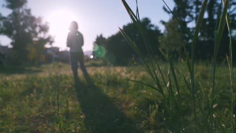 Kaukasischer-Junge-Verlässt-Den-Rahmen-In-Einem-Weizenfeld,-Verschwommener-Hintergrund-Mit-Sonneneruption-In-Der-Szene-4k