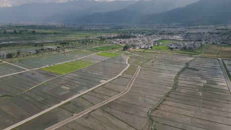 Cinematic-aerial-footage-of-the-Xi-Zhou-Paddy-Fields,-tribal-villages-of-the-Bai-Tribe-and-the-grand-Cangshan-Mountain-in-Dali,-Yunnan-Province-in-China