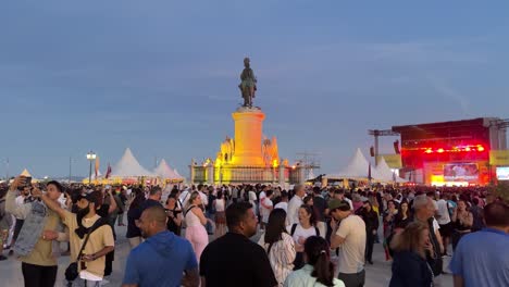 People-walking,-taking-photos,-and-partying-in-Arraial-Lisboa-Pride-at-Praça-do-Comércio-Square,-Lisbon,-Portugal