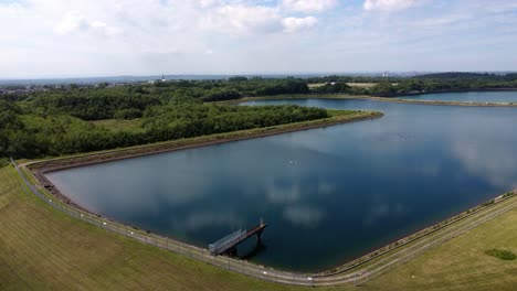 Vista-Aérea-Elevarse-Por-Encima-Del-Depósito-De-Suministro-De-Agua-Idílico-Cielo-Azul-Reflejos-En-El-Lago-Rural