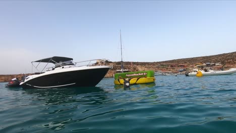 Unused-floating-AquaRocket-towable-sofa-tied-to-a-boat,-waiting-for-people-on-the-Mediterranean-Sea-in-Comino,-Blue-Lagoon,-Malta