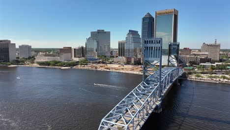 Mirrored-modern-high-rise-towers-in-Jacksonville-Town-during-sunny-day,-Florida,-Cruising-boat-on-river