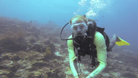 A-diver-takes-a-selfie-with-a-coral-reef-backdrop-in-Raja-Ampat,-Indonesia