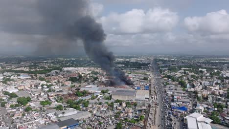 Schwarzer-Rauch-Steigt-Aus-Einem-Brand-Auf,-Der-Eine-Fabrik-Neben-Der-Autobahn-Nach-Santo-Domingo-Verwüstet,-Drohne