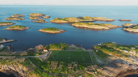 Flying-towards-the-famous-and-beautiful-Henningsvaer-football-field-on-the-Lofoten-Islands-during-the-sunset,-seeing-beautiful-islets