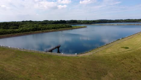 Water-supply-reservoir-aerial-view-rising-over-rural-establishing-idyllic-countryside-lake-supply