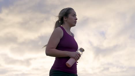 Woman-standing-on-hill-after-workout-contrast-sunrise-sky-behind