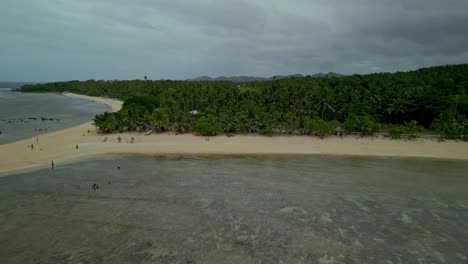 Aerial-push-in-of-distant-people-on-beach-on-island-in-Philippines