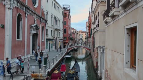 Narrow-quiet-street-in-Venice,-view-of-small-canal,-bridge-and-gondolas