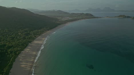 Idyllic-beach,-ocean-and-green-hills-in-Philippines,-wide-aerial-pull-out