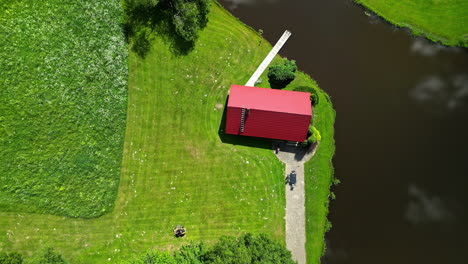 Mowing-the-lawn-at-a-countryside-cottage-and-pond---straight-down-aerial-time-lapse