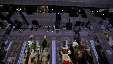 Tilt-down-from-ceiling-to-display-of-high-fashion-outfits-displayed-on-mannequins