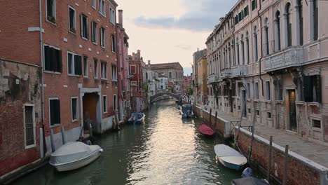 Rosy-sunset-on-quiet-canal-in-Venice,-soft-light-on-rippling-peaceful-water