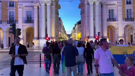 Dolly-in-of-tourists-and-a-lady-placed-the-New-Progress-Pride-Flag-on-the-back-of-her-body-at-Praça-do-Comércio-Square,-Lisbon,-Portugal,-celebrating-the-Arraial-Lisboa-Pride