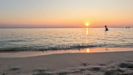 Beautiful-sunset-on-a-paradise-island-on-Maldives,-couple-paying-on-the-background