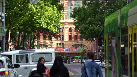 La-Bulliciosa-Ciudad-De-Melbourne,-Con-Tranvías-Recorriendo-Elizabeth-Street-Y-La-Estación-De-Flinders-Street-Con-Decoraciones-Festivas-Durante-La-Temporada-Navideña,-Ejemplifica-Una-Vibrante-Escena-Urbana.